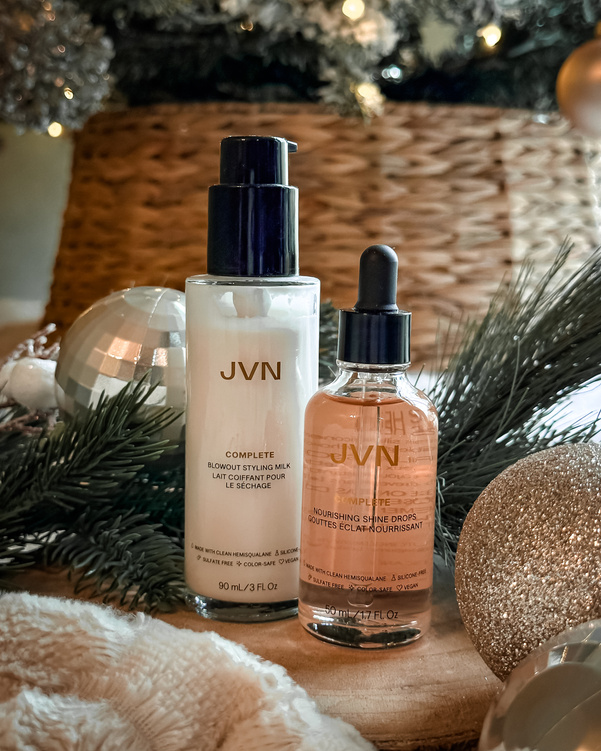 holiday product display of two JVN haircare products in front of a Christmas tree and ornaments 